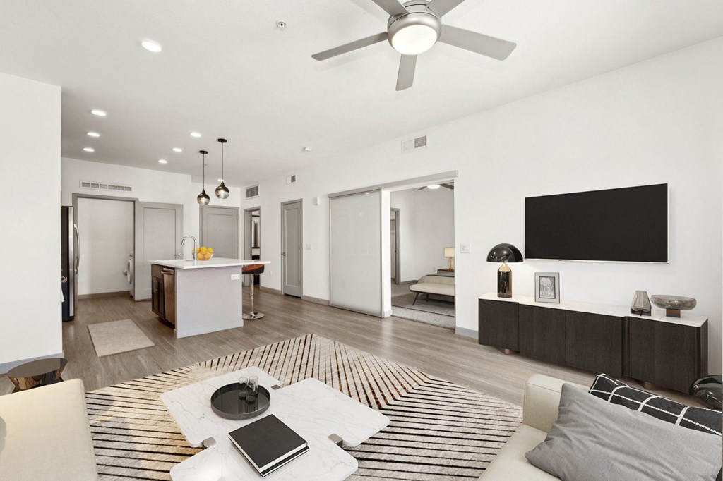 an open living room with a kitchen and a ceiling fan