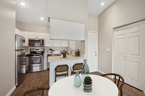 an open kitchen and dining room with stainless steel appliances and a white table