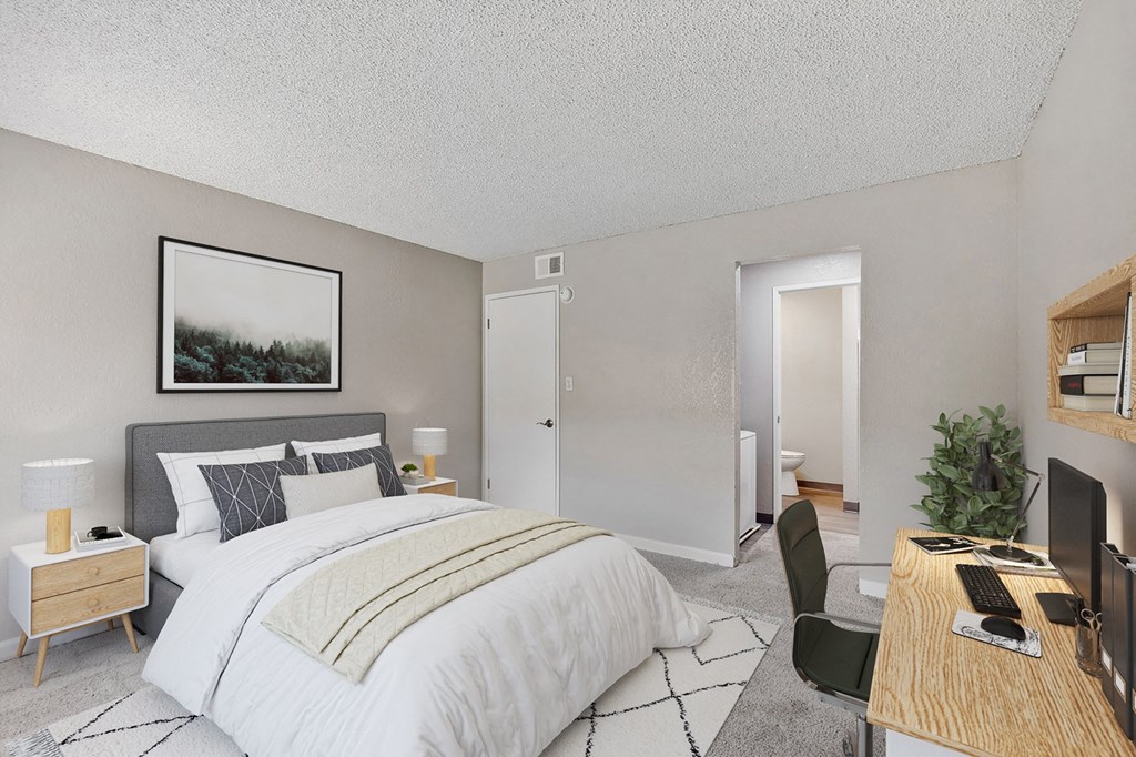 an open bedroom with a bed and a desk with a computer