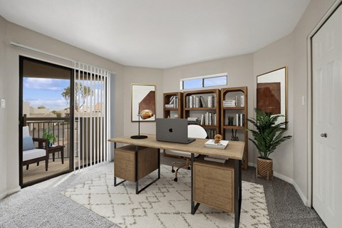 a home office with a laptop on a desk and a door to a balcony