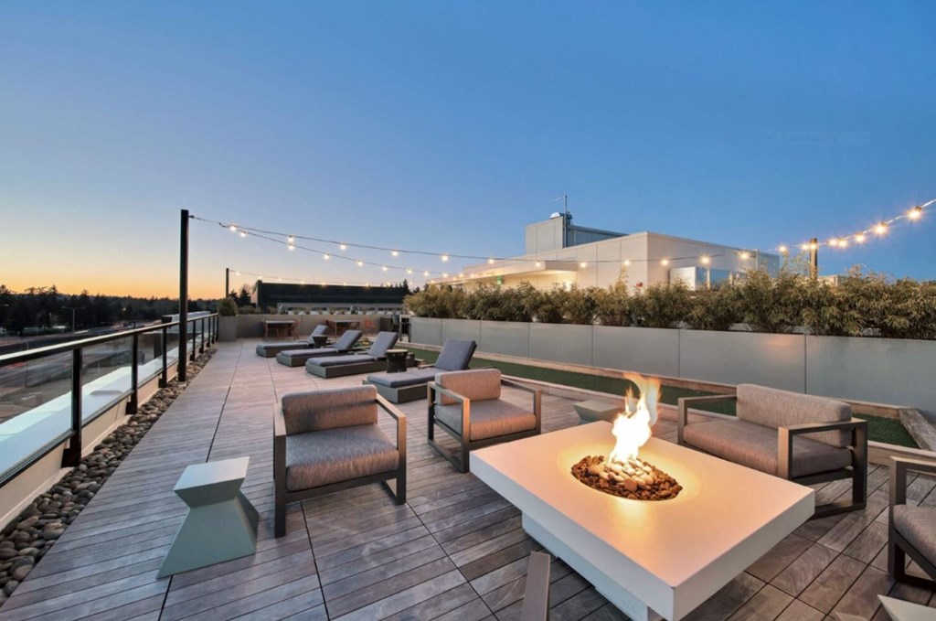 a rooftop lounge with a fire pit and tables