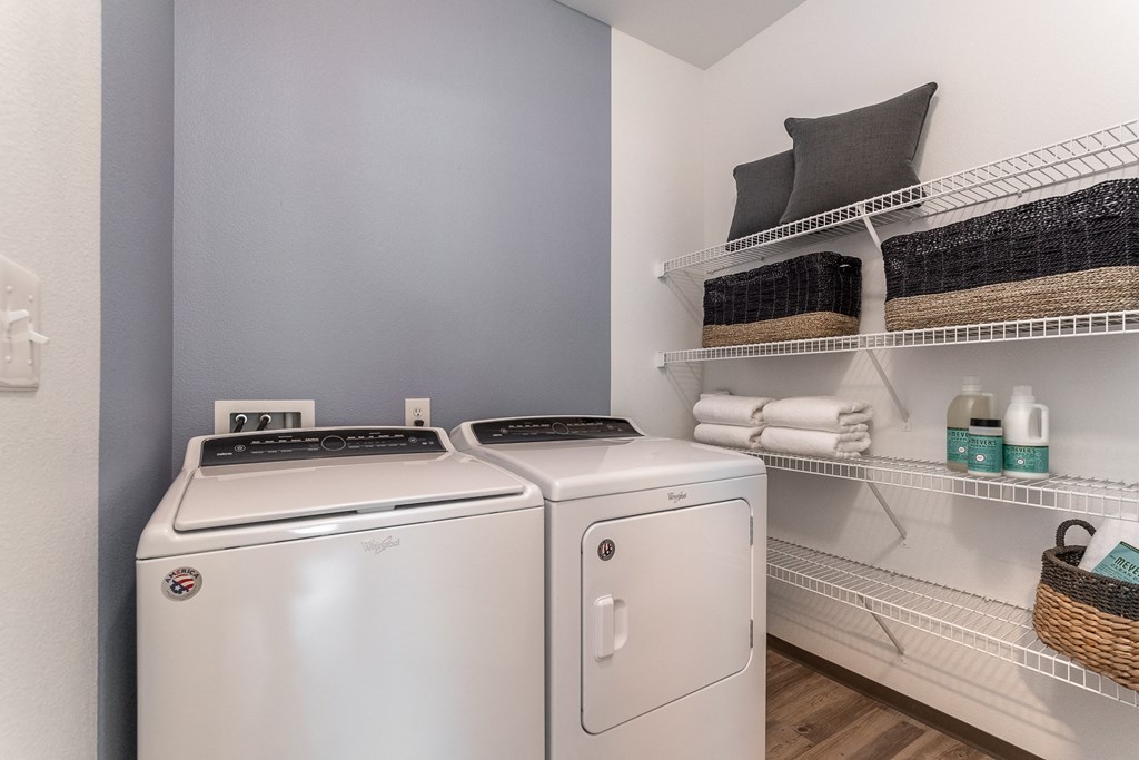 a laundry room with a washer and dryer and a shelf with towels