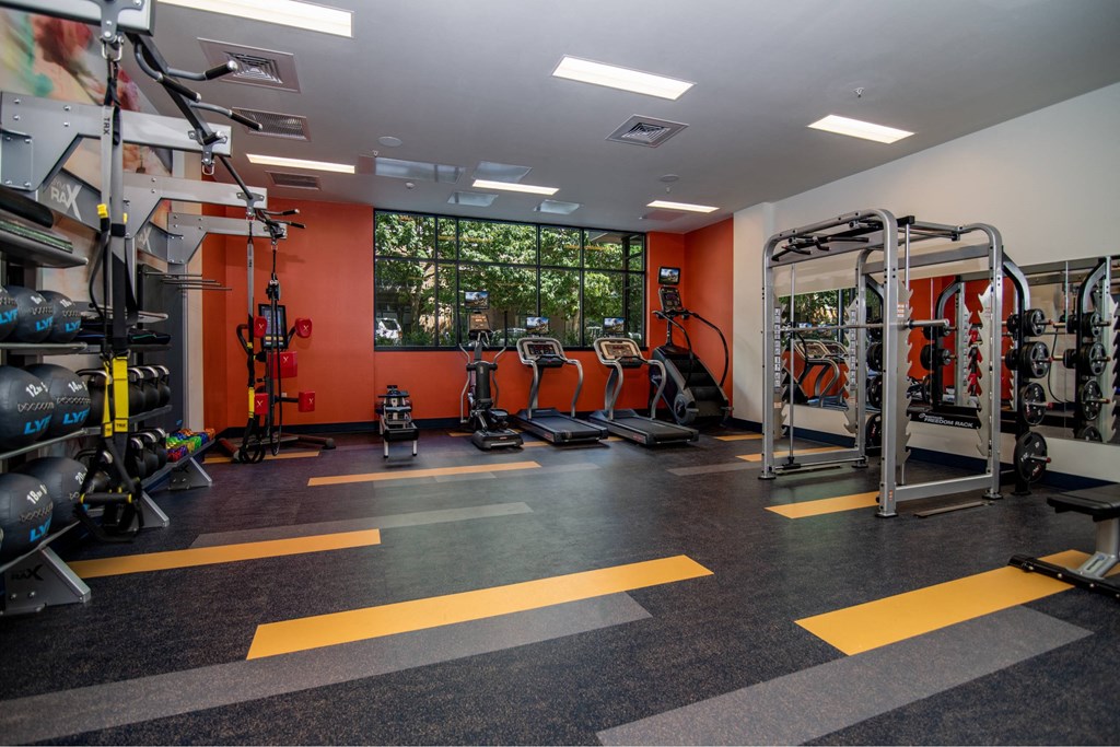 a gym with weights and cardio equipment and a window