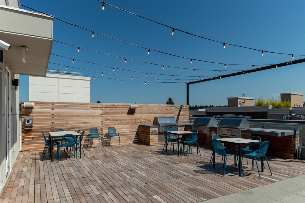 a roof deck with tables and chairs and a barbecue grill