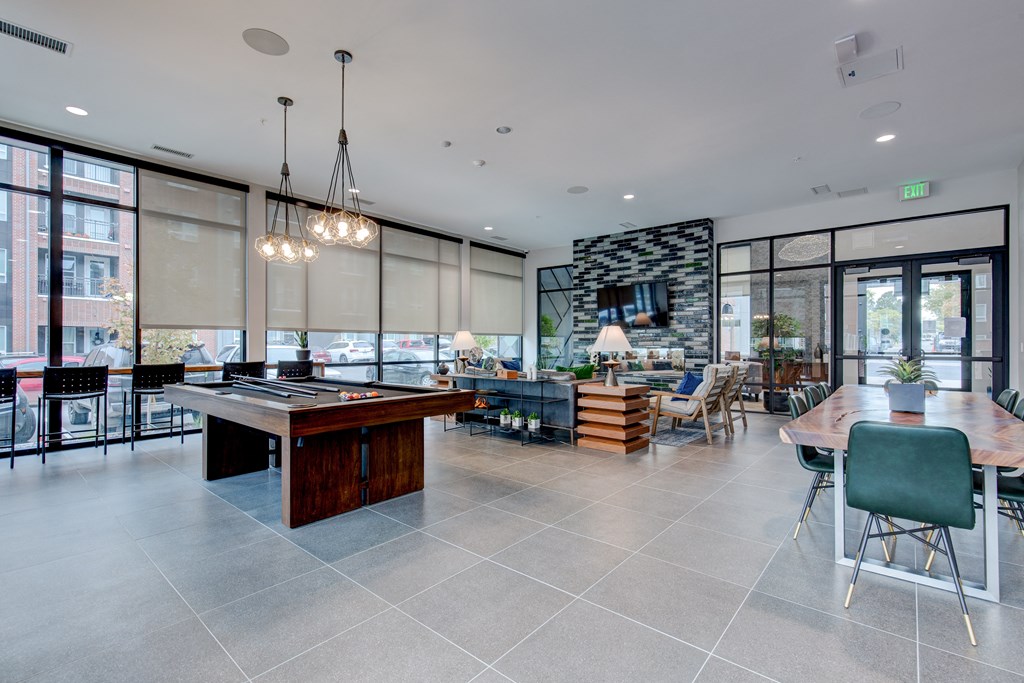 a communal area with a pool table and a dining area with chairs and tables