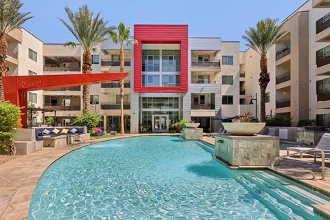 A red building with a pool in front of it.
