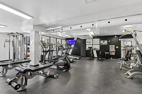 A gym with a variety of equipment including treadmills, weights, and exercise machines.