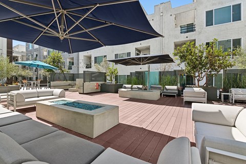 A patio with a pool and chairs under a blue umbrella.