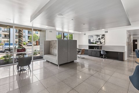A spacious living room with a grey sofa and a large window overlooking a parking lot.