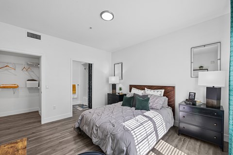 A bedroom with a bed, nightstand, and a mirror on the wall.