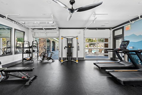 A gym with treadmills, exercise bikes, and a fan.