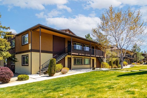 A modern house with a brown and beige exterior and a large front yard.