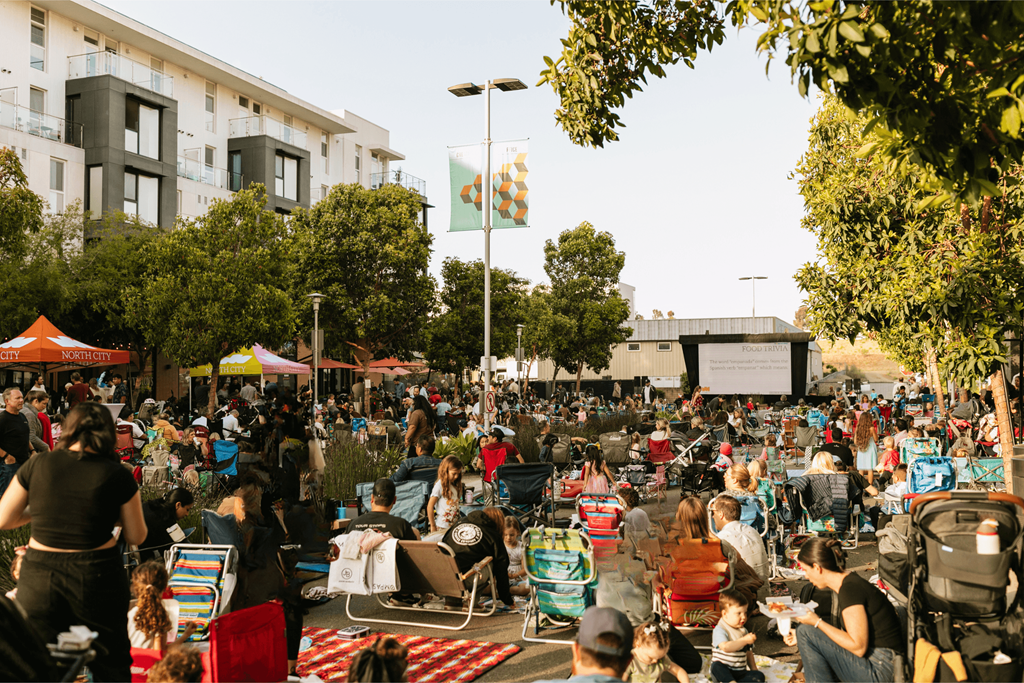 A large crowd of people are gathered in a park for an outdoor event.
