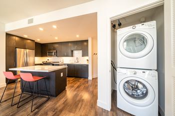 A modern kitchen with a washer and dryer built into the wall.