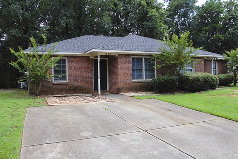 a small brick house with a driveway in front of it