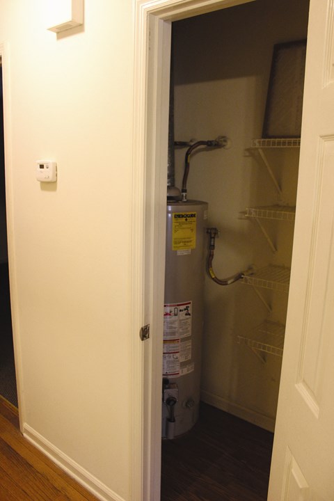 a closet with a water heater in it and a white door