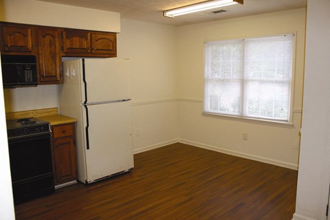 an empty kitchen with a refrigerator and a window