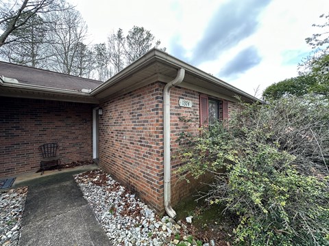 the side of a brick house with a driveway and a bench