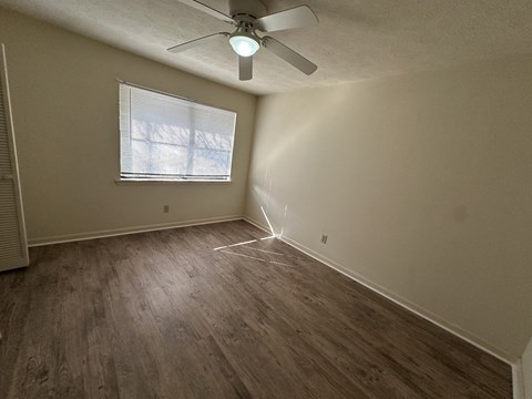 A room with a ceiling fan and a window with blinds.