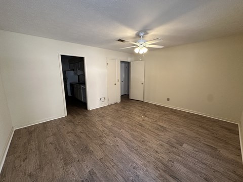 A room with a ceiling fan and a doorway leading to another room.