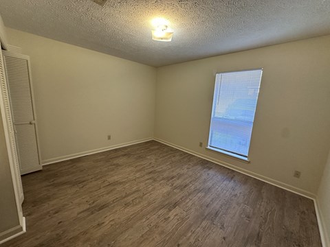 Empty room with wooden flooring and a window.