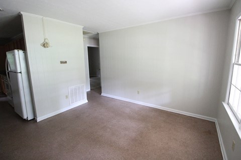 an empty living room with white walls and a refrigerator