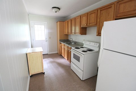 an empty kitchen with white appliances and wooden cabinets