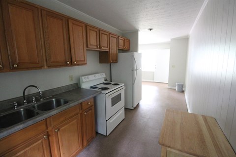 an empty kitchen with wooden cabinets and a white stove and refrigerator