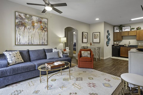 A living room with a grey couch, a coffee table, and a painting on the wall.