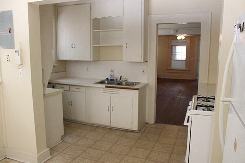 an empty kitchen with white cabinets and a sink