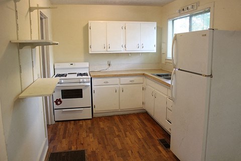 a kitchen with white cabinets and appliances and a refrigerator