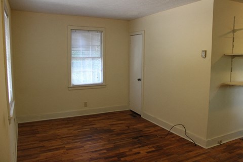 a room with a wooden floor and a window and a closet