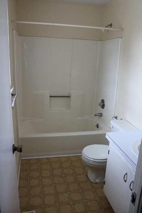 a white bathroom with a toilet and a bath tub