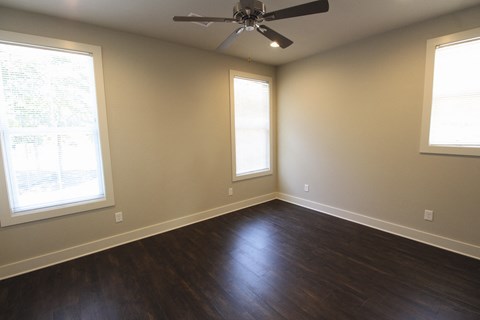 an empty living room with wood floors and a ceiling fan