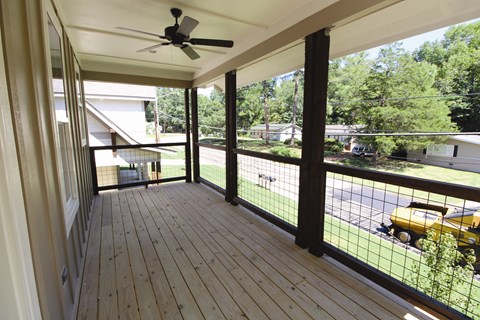 a screened in porch with a view of the yard and a ceiling fan