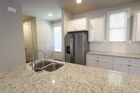 a kitchen with a granite counter top and a stainless steel refrigerator