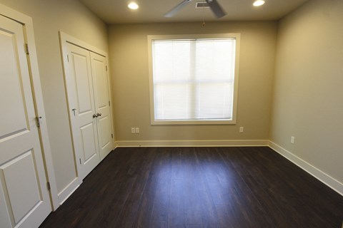 an empty living room with wood floors and a window