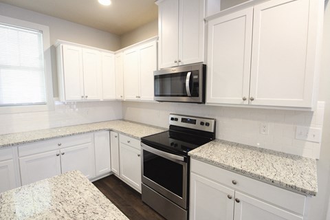 a kitchen with white cabinets and granite counter tops