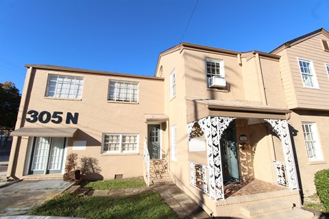 A two-story house with a beige facade and a white archway entrance.
