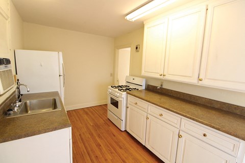 A kitchen with white cabinets and a stove top oven.