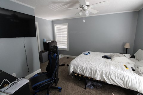 a bedroom with a bed and a ceiling fan and a tv