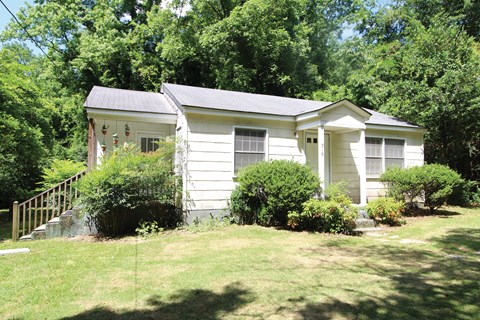 a small white house with a yard and trees