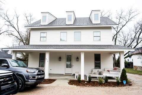A white house with a grey car parked in front.