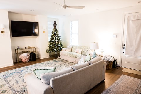 A living room with a Christmas tree and a grey couch.