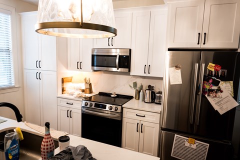 A kitchen with white cabinets and a black refrigerator.
