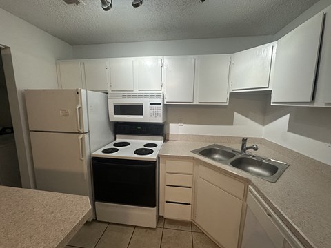 A kitchen with a stove, sink, and cabinets.