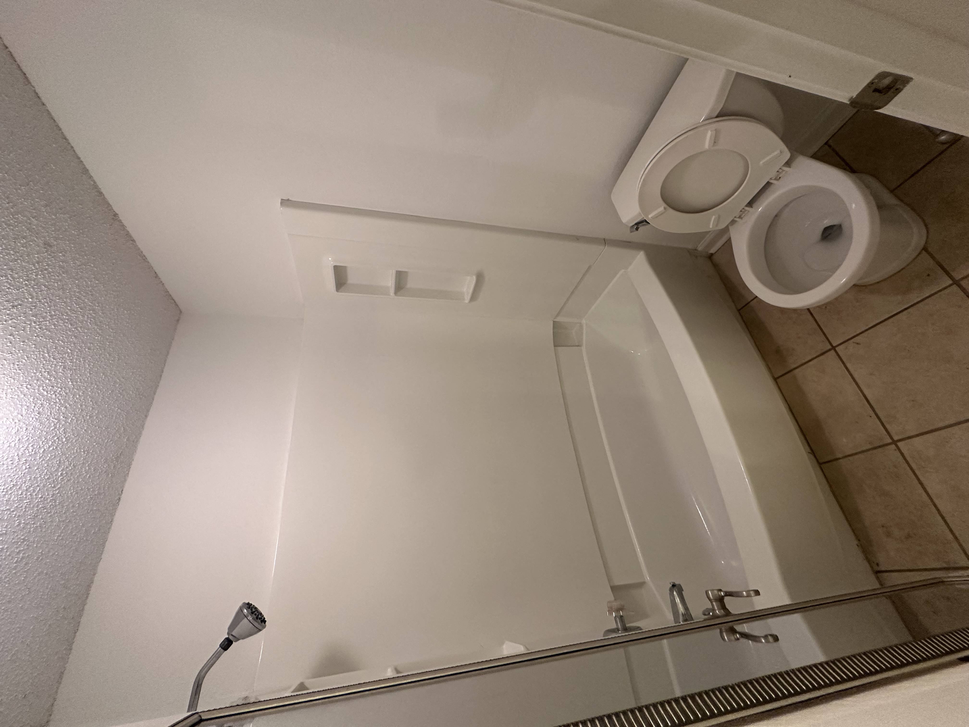 A white toilet is installed in a bathroom with a glass shower stall.