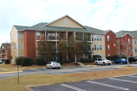 an apartment building with cars parked in a parking lot
