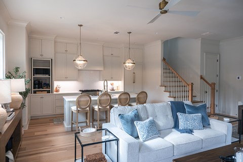 A living room with a white couch and a kitchen area in the background.