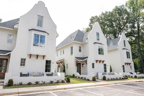 A white house with a black roof and a green lawn in front.